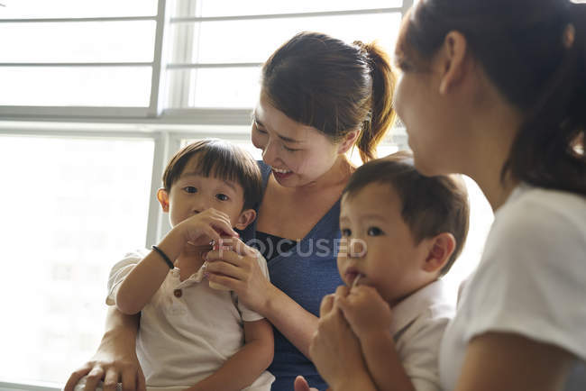 Junge Mütter beim Binden mit ihren Kindern im Wohnzimmer — Stockfoto