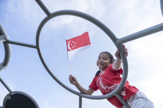 Porträt eines stolzen singaporeanischen Kindes mit Nationalflagge — Stockfoto