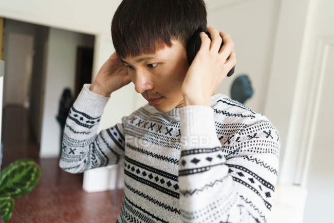 Молодий азіатський чоловік в навушниках вдома — стокове фото