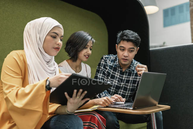 Junge multikulturelle Geschäftsleute, die mit digitalen Geräten im modernen Büro arbeiten — Stockfoto
