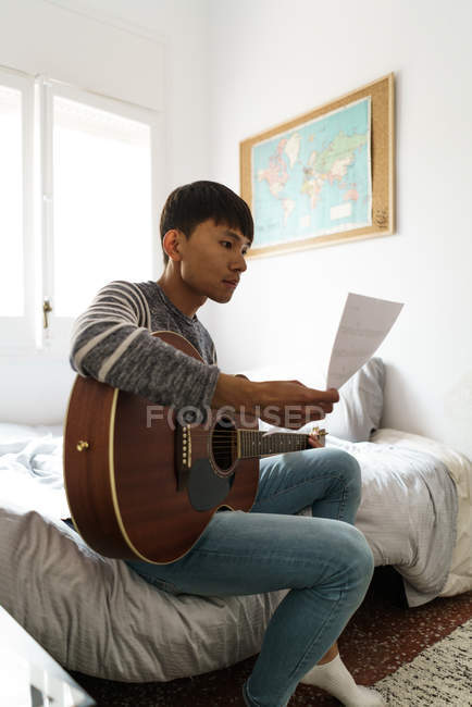 Jeune homme regardant ses partitions musicales — Photo de stock