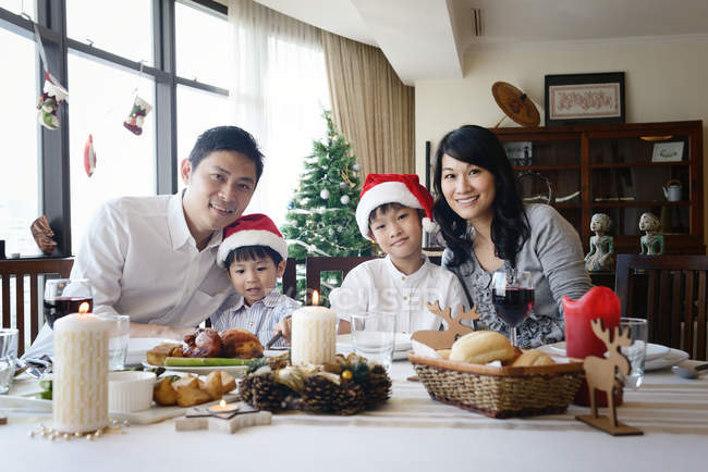 Happy asian family at christmas holidays sitting by table — Stock Photo