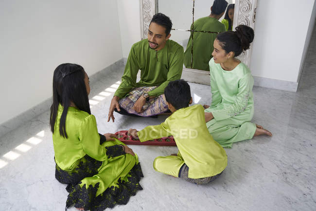 Junge asiatische Familie feiert Hari Raya zusammen zu Hause und spielt traditionelles Spiel — Stockfoto