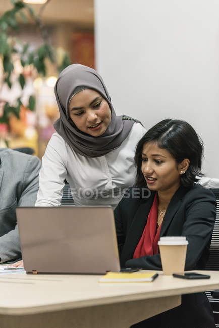 Молоді мультикультурні бізнесмени працюють з ноутбуком в сучасному офісі — стокове фото