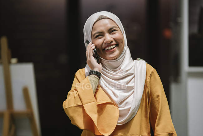 Young asian business woman in hijab using smartphone in modern office — Stock Photo