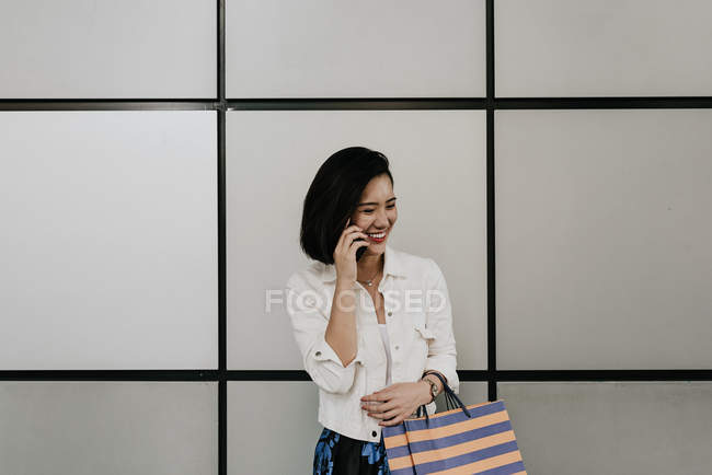 Молода випадкова азіатська жінка використовує розумний в торговому центрі — стокове фото