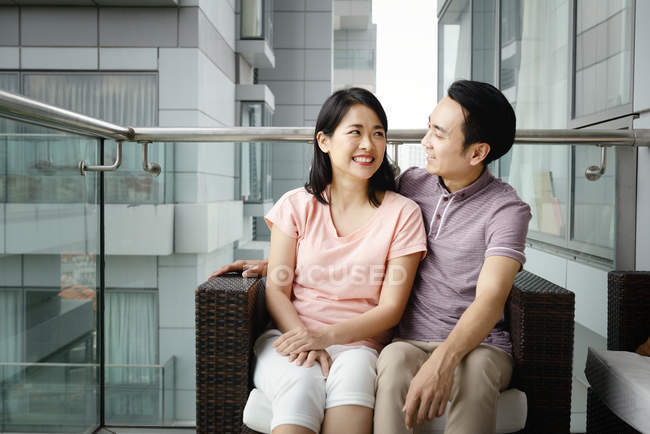 Mature asian casual couple sitting on armchair together — Stock Photo