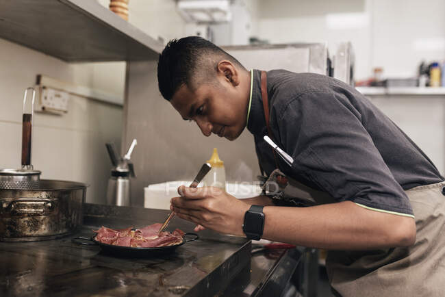 Junger asiatischer Koch kocht in Restaurantküche — Stockfoto