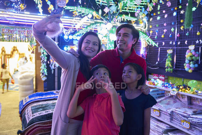 Familia alegre tomando selfies en Hari Raya Geylang Bazaar, Singapur - foto de stock