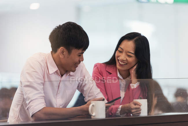 Attractive young asian couple using smartphone together — Stock Photo