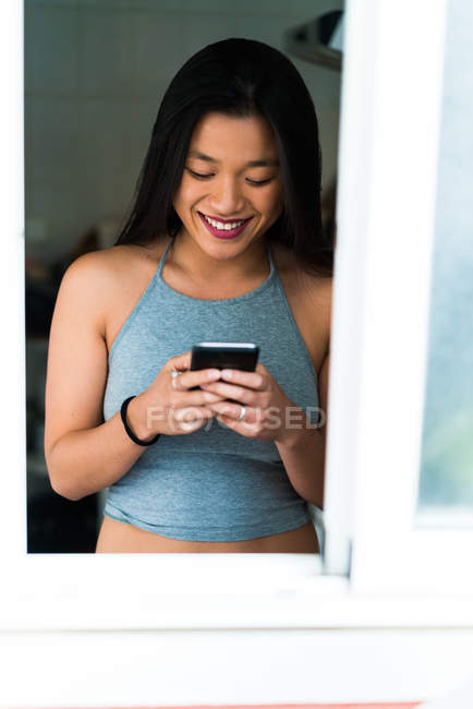Jeune attrayant asiatique femme en utilisant smartphone à la maison — Photo de stock