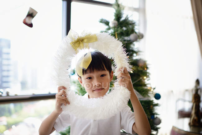 Familia asiática celebrando vacaciones de Navidad, niño con corona de Navidad - foto de stock