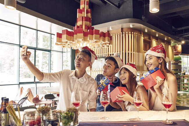 Compañía de jóvenes amigos asiáticos juntos celebrando la Navidad y tomando selfie - foto de stock