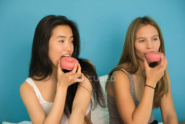 Two young women having fun with donuts — Stock Photo