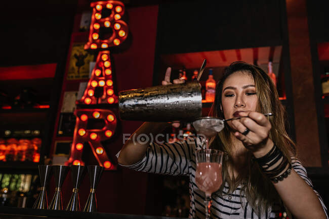 Retrato de una joven camarera haciendo cóctel en el bar - foto de stock