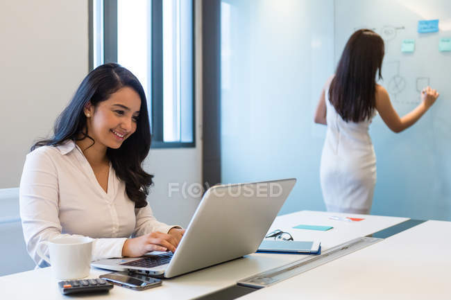 Two young women working in a conference room together — Stock Photo