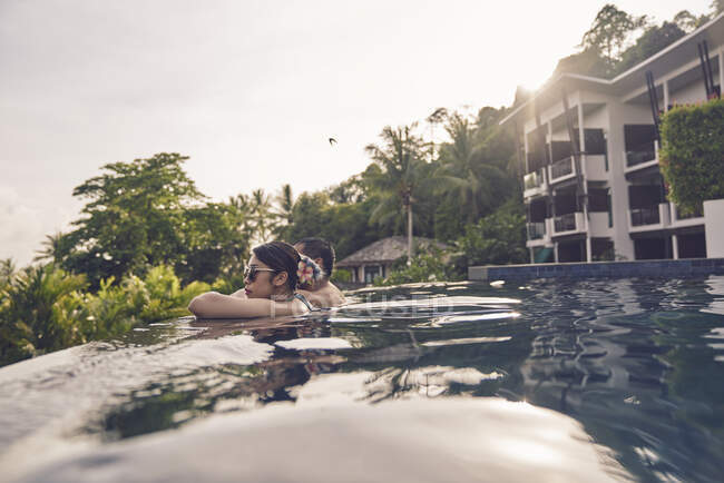 COMMUNIQUÉS Jeune couple asiatique se relaxant dans une piscine — Photo de stock