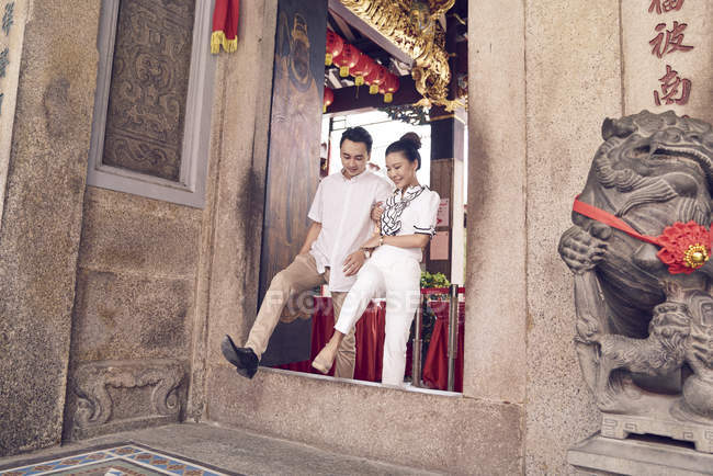Jeune homme et jeune femme marchant à travers l'espace de porte au temple. Singapour — Photo de stock