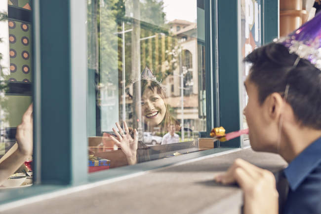 Young asian man looking through window at woman — Stock Photo