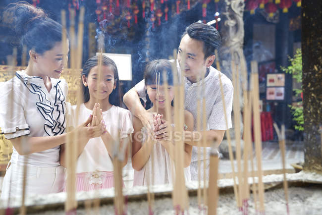 Семья, стоящая против свечей в древнем храме, Сингапур — стоковое фото