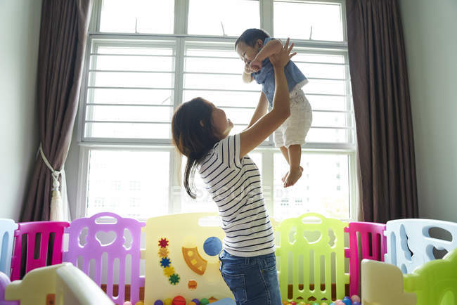 Mother carrying her child in the play room — Stock Photo