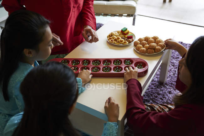 Young asian family celebrating Hari Raya in Singapore and playing traditional game — Stock Photo