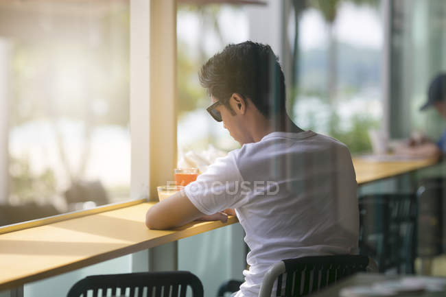 Young man having a drink and a quiet moment in a bar on Sentosa — Stock Photo