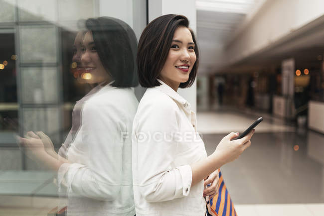 Jovem casual asiático mulher usando inteligente no shopping — Fotografia de Stock