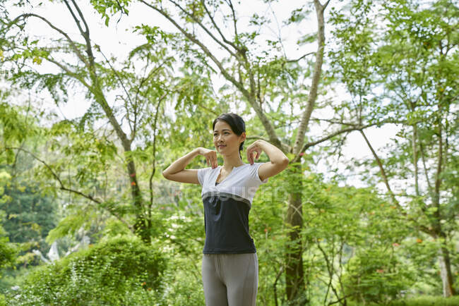 Frau wärmt sich vor ihrem Lauf im Botanischen Garten auf — Stockfoto
