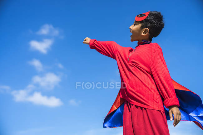 Superhero kid against blue sky background. — Stock Photo