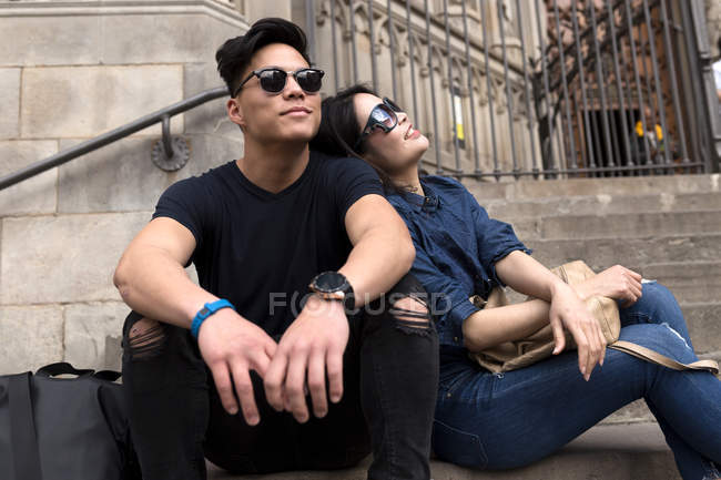 Jeune Chinois en lunettes de soleil assis ensemble sur les marches — Photo de stock