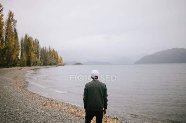 Молодой человек исследует пролив Милфорд, Новая Зеландия — стоковое фото