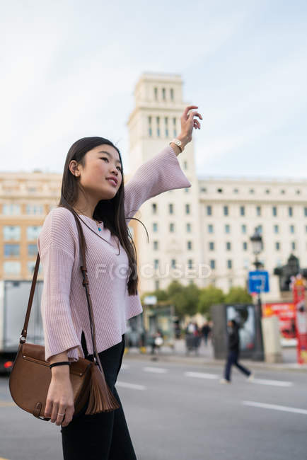 Jovem turista chinesa sinalizando um táxi — Fotografia de Stock
