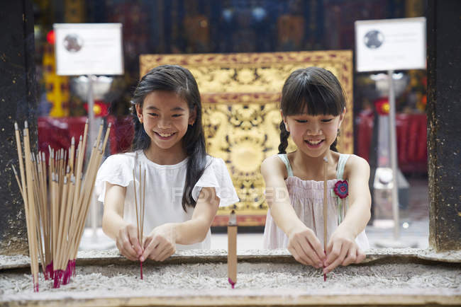 Дві молоді азіатські дівчата розміщують свічки в храмі — стокове фото