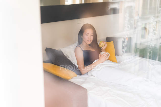 Chinese young and beautiful woman waking up in the morning and having breakfast in bed — Stock Photo