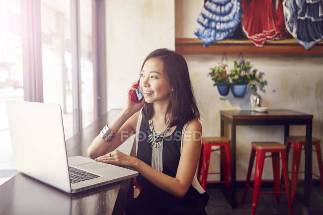 Jovem bela mulher asiática usando smartphone e laptop no café — Fotografia de Stock