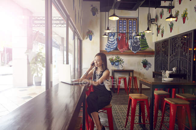 PROPRIETÀ Giovane bella donna asiatica utilizzando smartphone in caffè — Foto stock