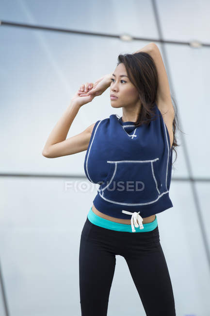 Uma jovem mulher asiática está se esticando antes de sua corrida na área da Marina Bay . — Fotografia de Stock