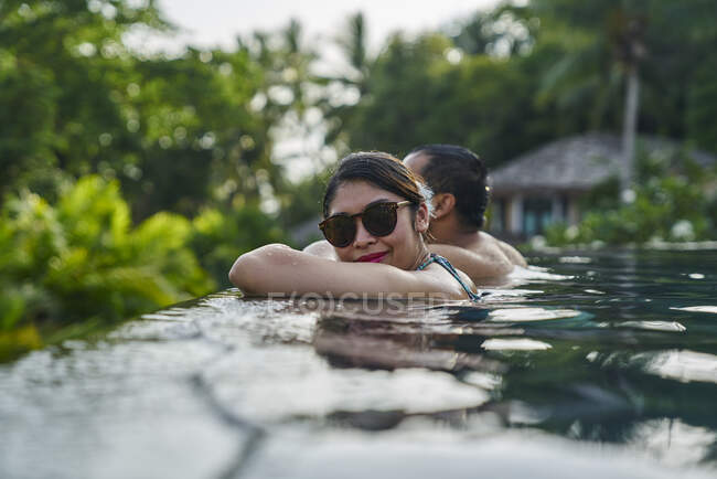 RELEASES Cheerful young asian couple relaxing in a pool — Stock Photo