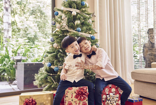 Happy asian family celebrating christmas together, portrait of two asian brothers with fir tree — Stock Photo