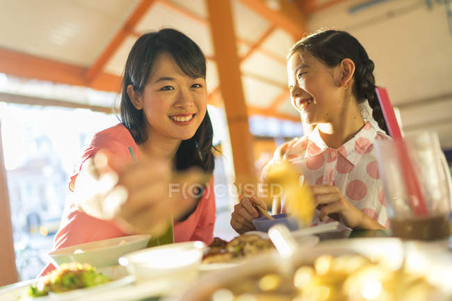 Happy asian mother and daughter eating food together — Stock Photo