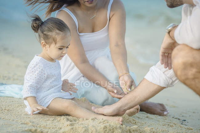 Família caucasiana feliz brincando com areia na praia — Fotografia de Stock