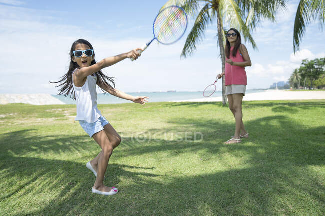 Madre e hija jugando bádminton en la playa - foto de stock