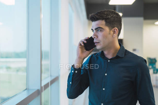 Giovane uomo d'affari asiatico parlando su smartphone in ufficio moderno — Foto stock