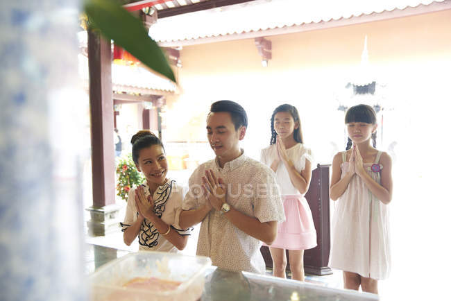 Giovane felice famiglia asiatica pregando nel santuario — Foto stock