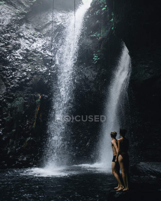 Parejas jóvenes explorando una cueva y una cascada en Bali - foto de stock