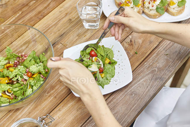 Immagine ritagliata di donna che cucina insalata in cucina — Foto stock