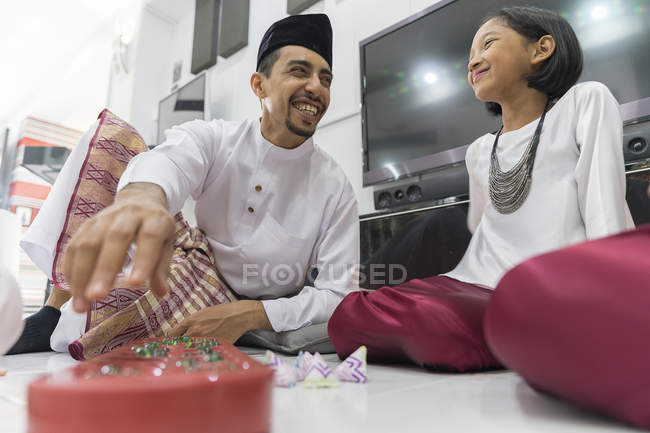 Glückliche asiatische Familie feiert Hari Raya zu Hause und spielt traditionelles Spiel — Stockfoto
