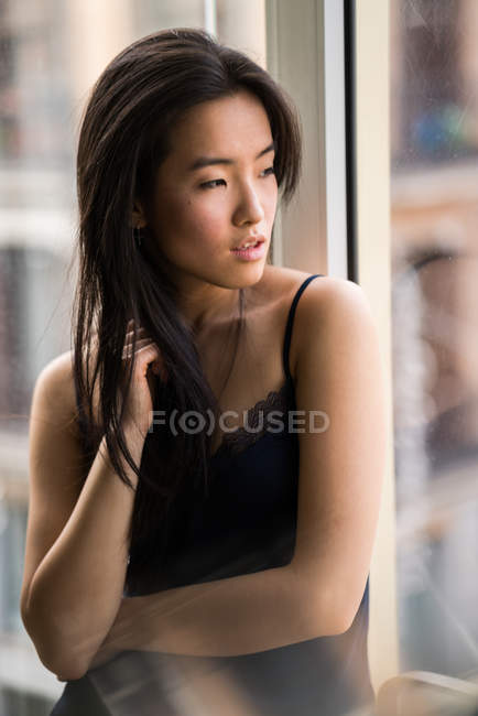 Retrato de hermosa mujer china en el interior junto a una ventana con luz natural - foto de stock