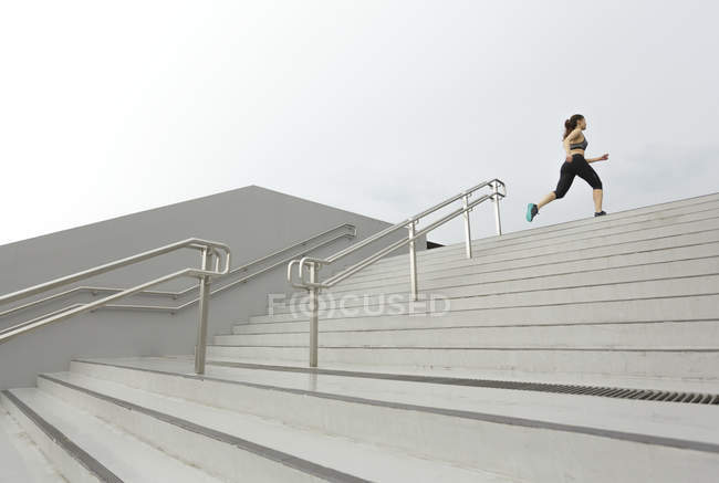 Eine junge asiatische Läuferin läuft in Singapore eine Treppe hinauf. — Stockfoto